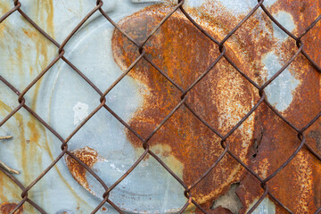 Rusty metal surface behind a chain-link fence in urban environment