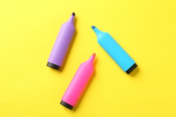 Bright highlighters on yellow background, flat lay
