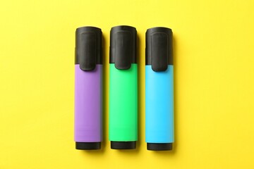 Bright highlighters on yellow background, flat lay