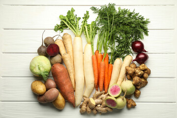 Different root vegetables on white wooden table, flat lay