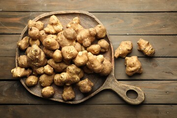 Raw Jerusalem artichokes on wooden table, top view