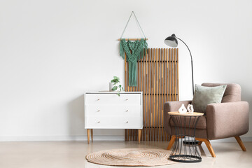 Interior of light living room with wooden folding screen, armchair and commode