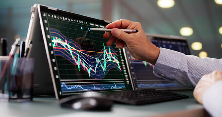 Stock Market Broker Looking At Graphs On Multiple Screens