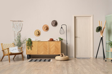 Modern interior of hallway with wooden commode, clothes hanger and hats