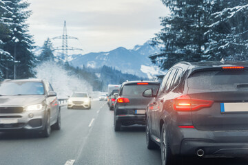Fototapeta premium Scenic view many cars stuck row mountain alpine forest road traffic jam cold winter day at Europe mountain resort. Automobile accident vehicle rush hour collapse. Vacation transport seasonal stuck.
