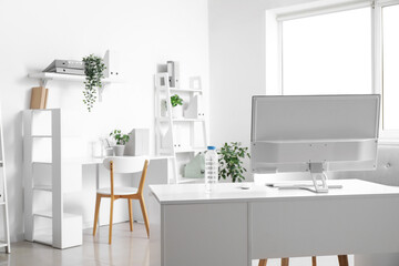 Bottle of water and computer on desk in light office