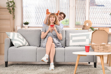 Obraz premium Young man with pieces of tasty pizza and his girlfriend holding cup of cola in living room