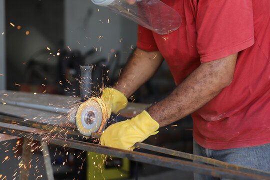 
Worker using grinder on metal. Blacksmith cutting metal.