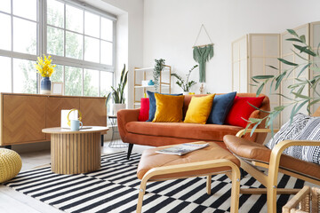 Interior of stylish living room with red sofa, table and armchair