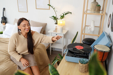 Young woman with record player on commode in bedroom