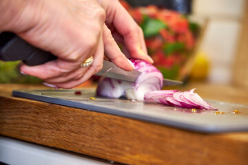 a woman cutting red onions for salad, top view, close-up