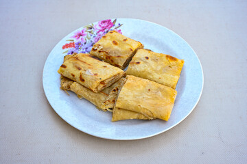 Freshly baked appetizing Turkish tortillas - Gozleme with spinach, cheese  on a white board. Space for text. Handmade Turkish traditional pastries. Ispanakli, otlu peynirli gozleme. Tahinli Katmer