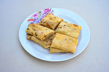 Freshly baked appetizing Turkish tortillas - Gozleme with spinach, cheese  on a white board. Space for text. Handmade Turkish traditional pastries. Ispanakli, otlu peynirli gozleme. Tahinli Katmer