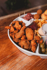 Close-up view of small milanesas, along with different snacks on a tray.