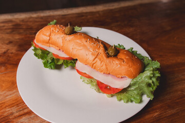 Large submarine sandwich on a plate on a wooden table.