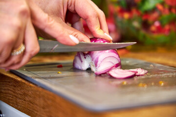 Obraz premium a woman cutting red onions for salad, top view, close-up