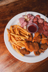 Detail view of a small plate with snacks on a wooden table.