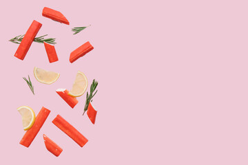 Tasty crab sticks with rosemary and slices of lemon flying on pink background © Pixel-Shot