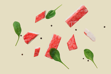 Cut tasty crab sticks with peppercorns and spinach leaves flying on green background © Pixel-Shot