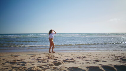 Carefree woman running sand beach at sea side in sexy swimsuit. Lady jogging