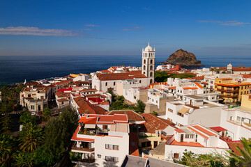 Fototapeta premium Panorama of Garachico town in Tenerife on a sunny winter day. Garachico rock island. Church with tall bell tower. Calm sunny day in the winter at Christmas time.
