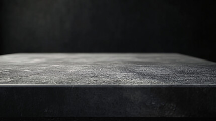 a dark stone countertop with a rough textured surface set against a moody black background with soft lighting

