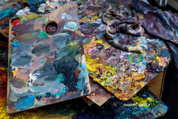 An old palette with oil paints in the artist's studio. Painted background created by a creative person. 