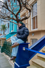 Happy young man on a street of colorful houses in London on sightseeing visit