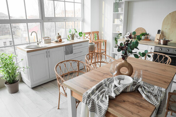 Interior of light kitchen with dining table, counters and shelf unit