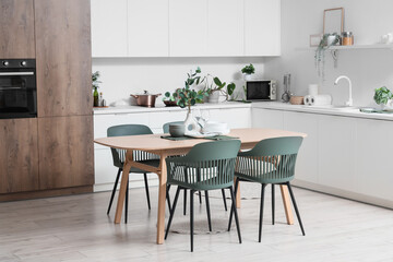 Interior of light kitchen with dining table, counters and plants