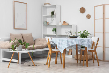 Interior of light dining room with table, couch and shelf units