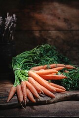 Vibrant orange carrots with lush green tops rest atop a rustic wooden surface, celebrating the...