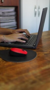 Close-up of woman typing for her work on her laptop from home with bracelet in her hand