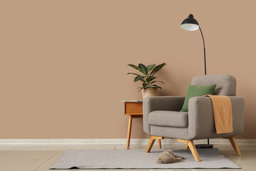 Armchair, slippers and houseplant on bedside table near brown wall in room