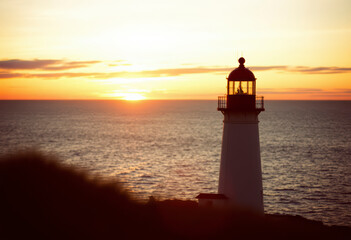 Fototapeta premium Beautiful sunset casts vibrant colors over the Atlantic Ocean near Peggy's Cove, highlighting the iconic lighthouse against the horizon.
