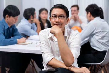 Engineer team leader portrait with diverse group of civil engineer and client working together on architectural project, reviewing construction plan and building blueprint at meeting table. Prudent