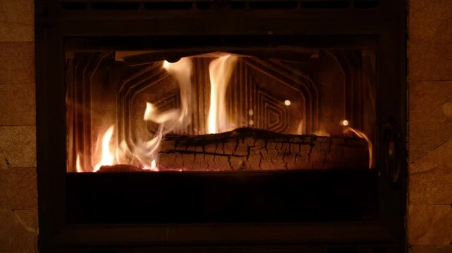 A gentle fire blazes in the hearth, warming coffee-beige tile with flickering light. A charred log glows red at the cracks, while subtle shadows dance on metal surfaces, forging a cozy vibe.