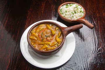 Bamya, a delicious okra stew, served with rice in traditional terracotta bowls, representing...