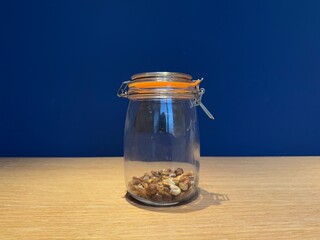 Half empty jar of nuts on blue background