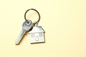 Metallic key with keychain in shape of house on color background
