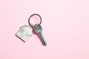 Metallic key with keychain in shape of house on color background