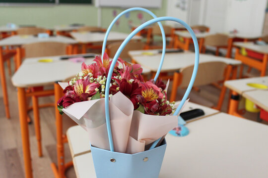 A basket of flowers on a desk in an empty elementary school classroom. First lesson after vacation at school
