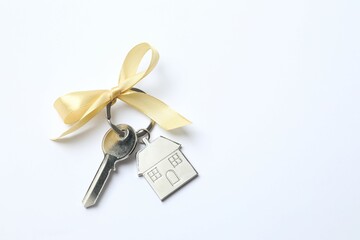 Metallic key with keychain in shape of house on white background