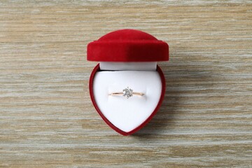 Beautiful shiny gold engagement ring with large diamond gemstone in a rich red velvet box on the...