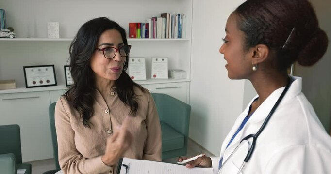 African nurse shaking hand of mature woman patient at meeting, making health insurance deal, express gratitude for getting professional medical consultation at appointment in clinic. Good health news