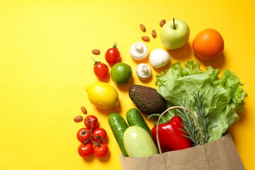 Paper bag, vegetables and fruits on color background