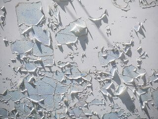 white aged paint on a wall with huge cracks that start peeling