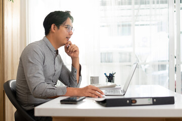 Man working in the morning, next to the window, inside the office