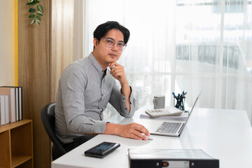 Young businessman sitting at a desk looking at camera