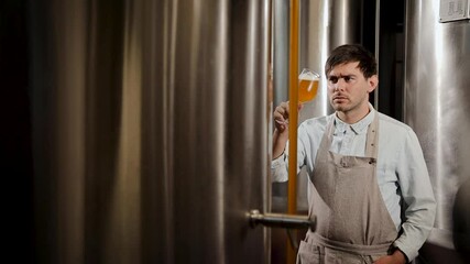 A dedicated brewmaster examines a glass of crafted beer while working in a brewery, ensuring cooking beer quality - Powered by Adobe